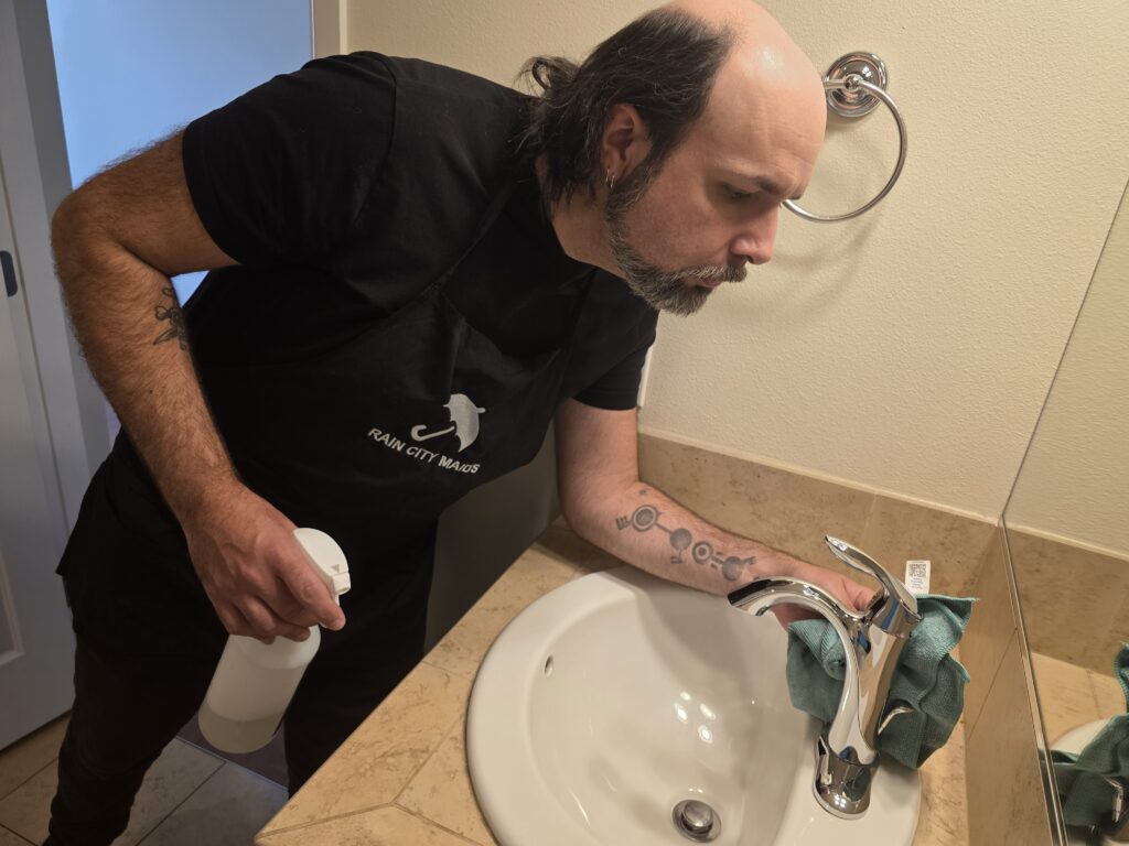 A Rain City Maids cleaner cleaning a bathroom sink