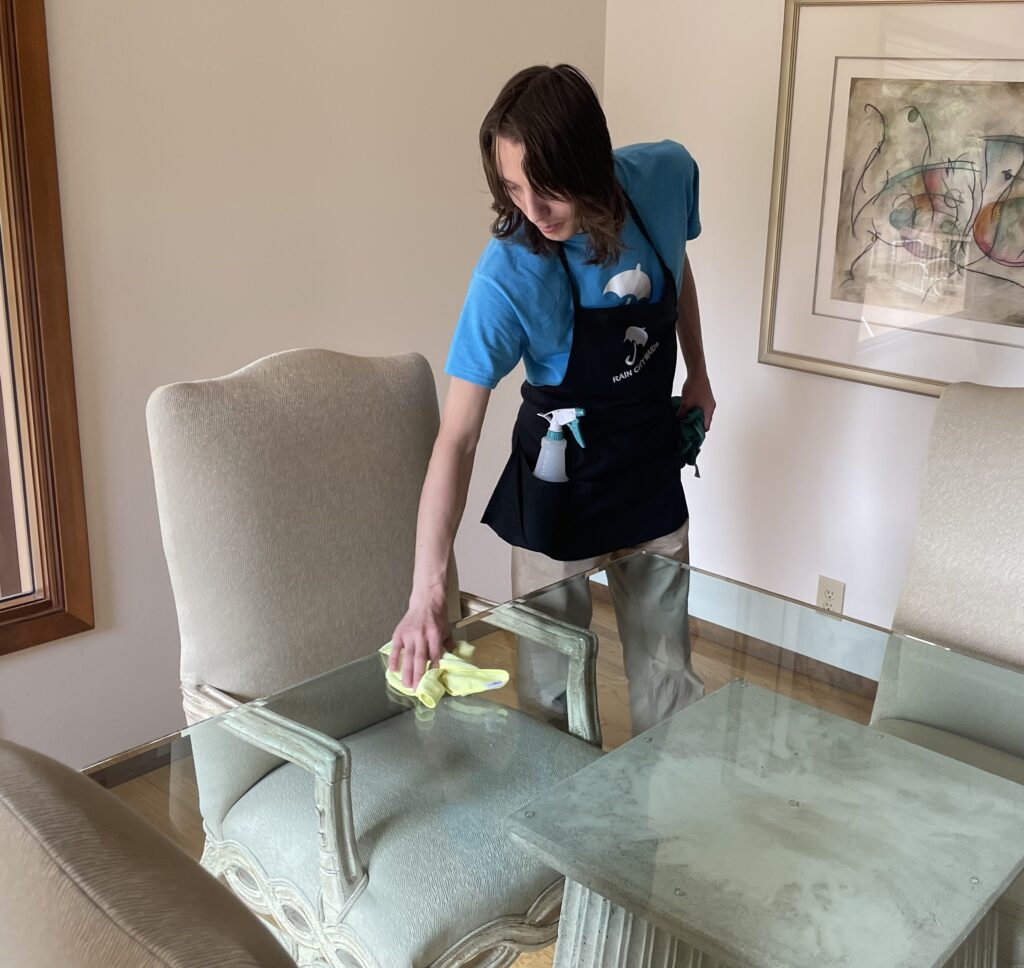 A Rain City Maids cleaner cleaning a glass table top