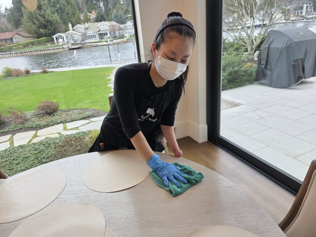 A Rain City Maids cleaner wiping down a dining table