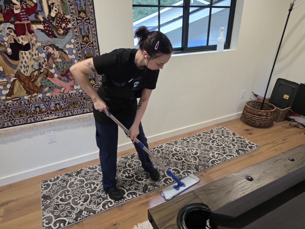 A Rain City Maids cleaner mopping a hardwood floor
