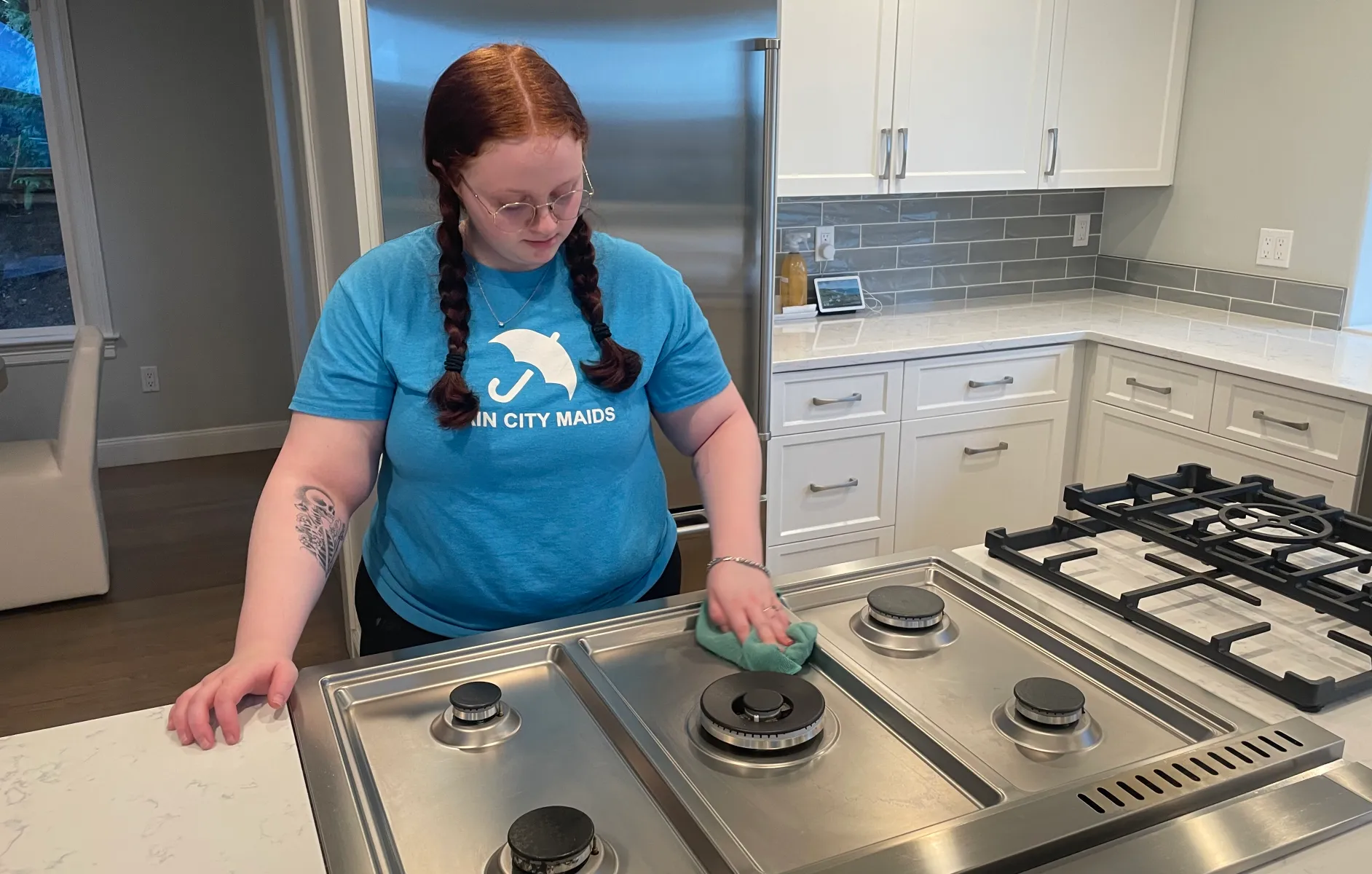 A Rain City Maids house cleaner cleaning a kitchen cooktop