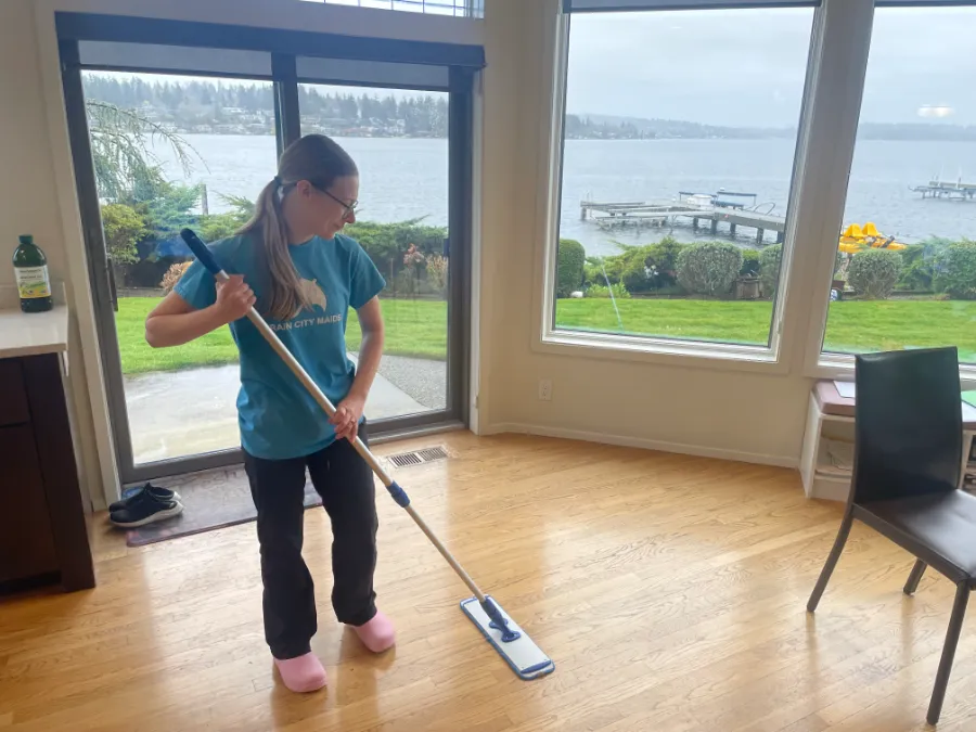 A Rain City Maids cleaner mopping in front of a water view