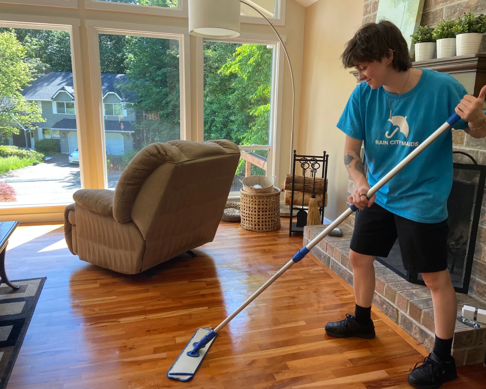 A Rain City Maids cleaner mopping a bright living room with large windows