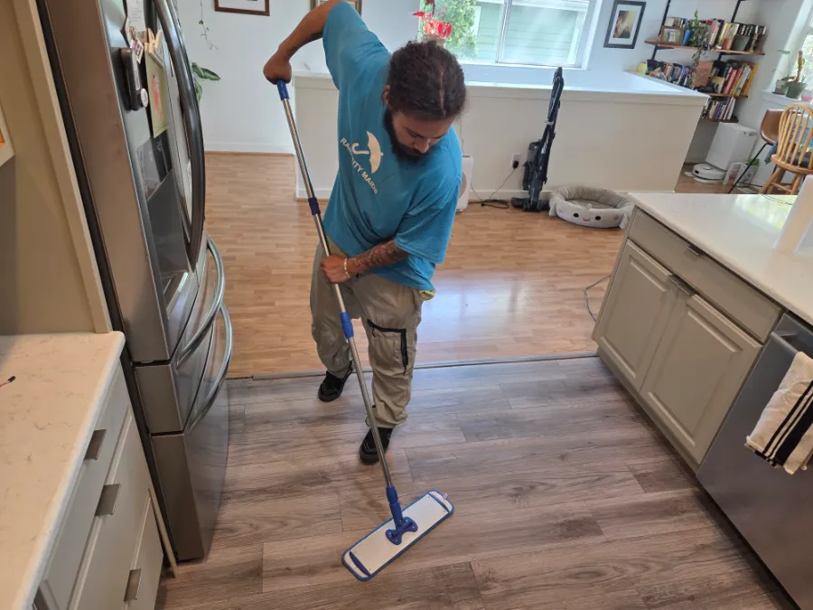 A Rain City Maids cleaner mopping a kitchen floor