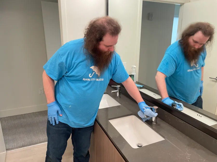 A Rain City Maids cleaner wiping a bathroom counter