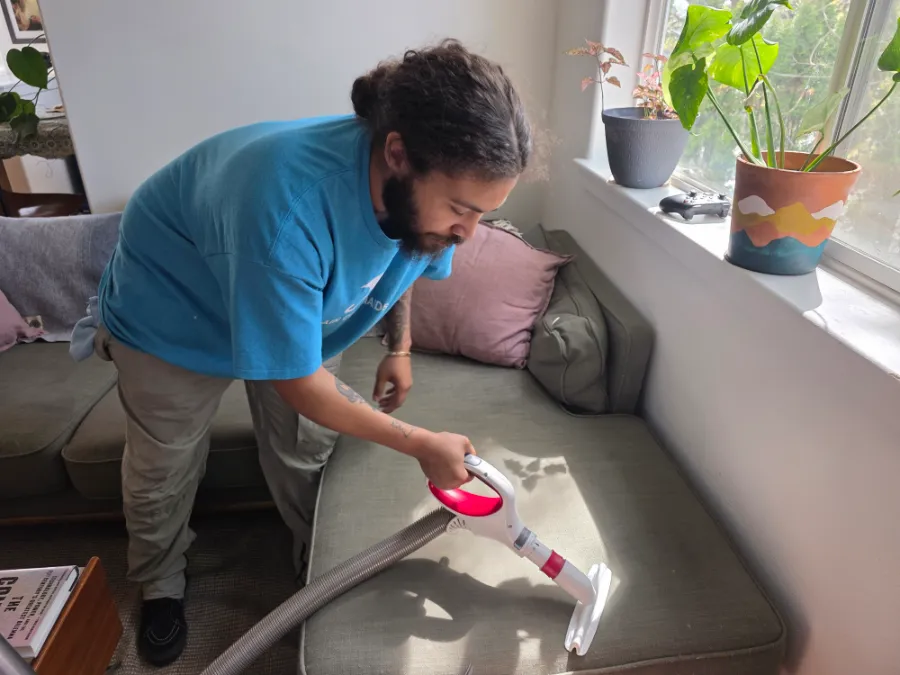 A Rain City Maids cleaner vacuuming a couch