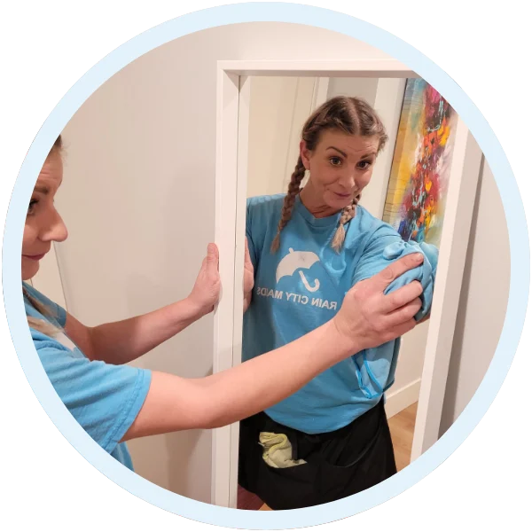 Rain City Maids cleaner wiping a mirror