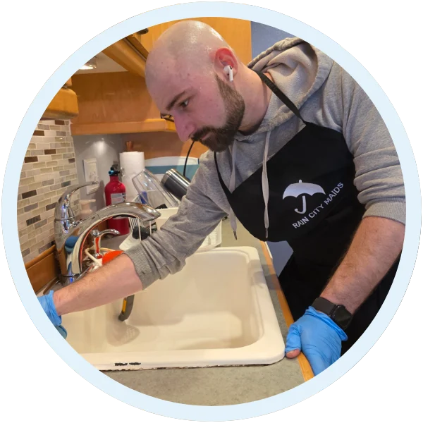 Rain City Maids cleaner scrubbing a kitchen sink